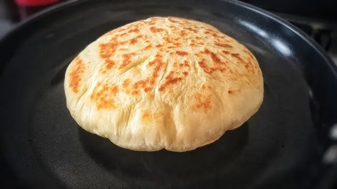 A round food item on a black surface.