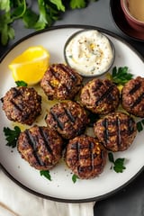A plate of meatballs with a side of sauce.
