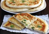 A stack of pita bread with green toppings.