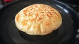 A round food item on a black surface.