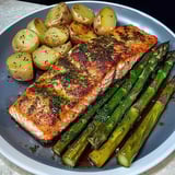 A plate of food with fish, potatoes and asparagus.