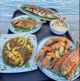 A table full of food including shrimp, rice, and fish.