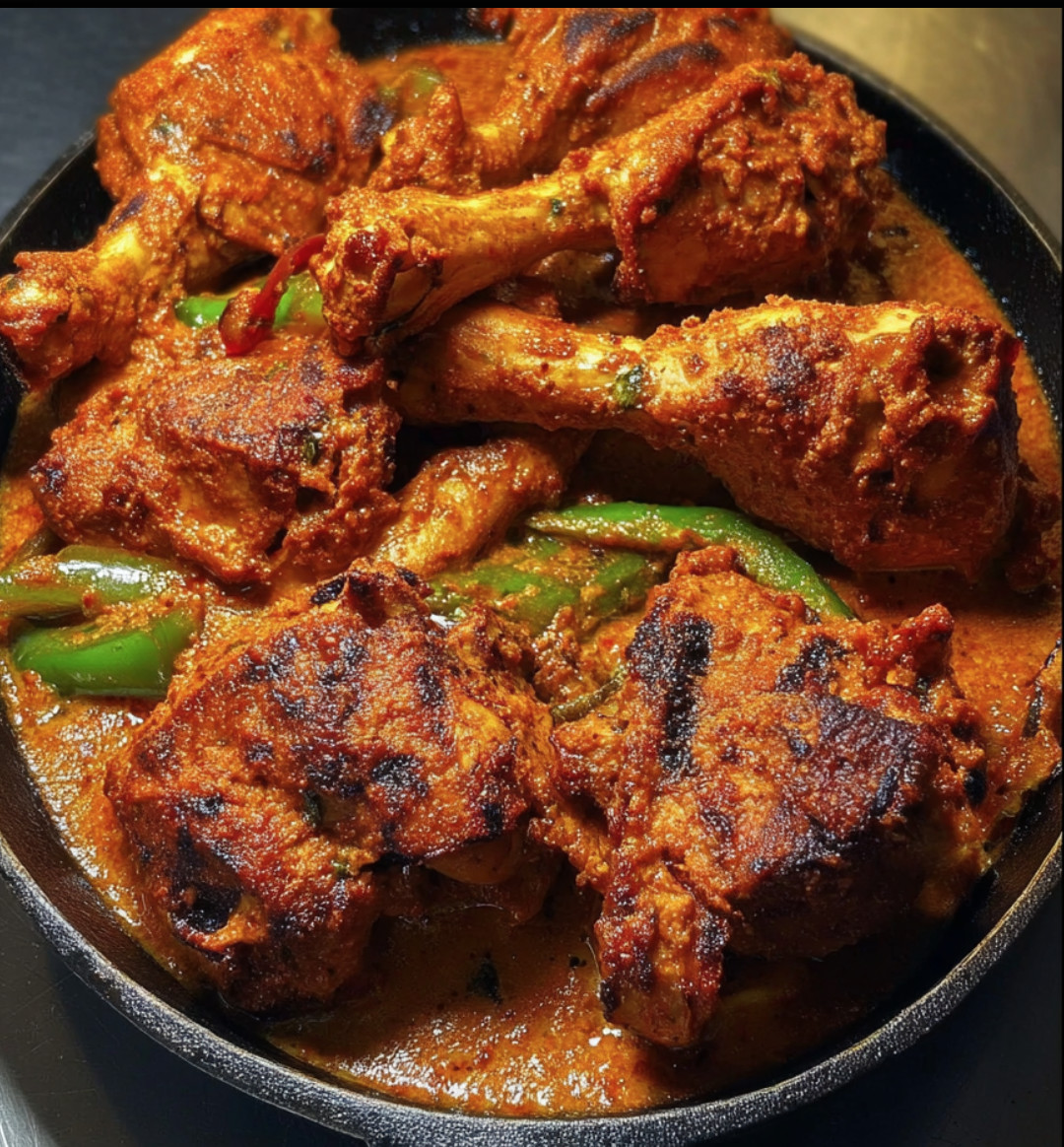 A pan of chicken with peppers and sauce.