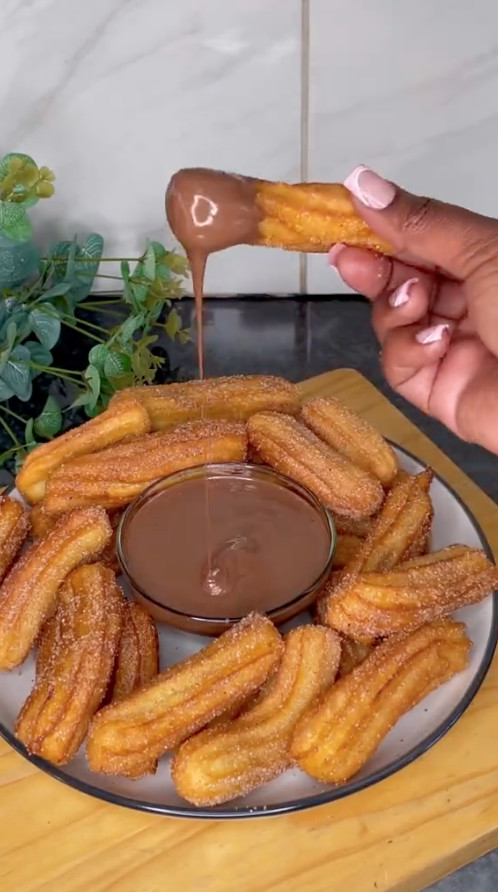 A plate of churros with chocolate drizzled on top.