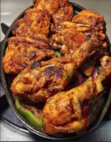A pan of chicken with peppers and onions.