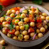 A bowl of food with tomatoes, cucumbers, and chickpeas.